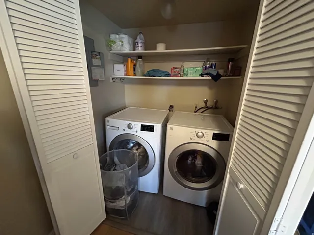 Laundry area with electric panel, washer and dryer, and dark wood-style floors
