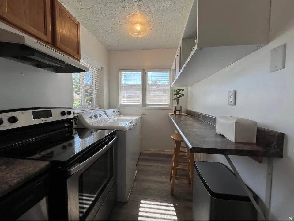Laundry area with a textured ceiling, dark wood-style floors, and washing machine and clothes dryer