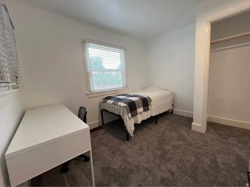 Bedroom with dark carpet and baseboards