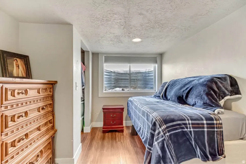 Bedroom with a textured ceiling and light wood-style floors