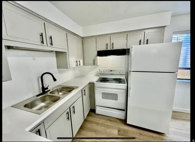 Kitchen with white appliances, light countertops, and light wood-style floors