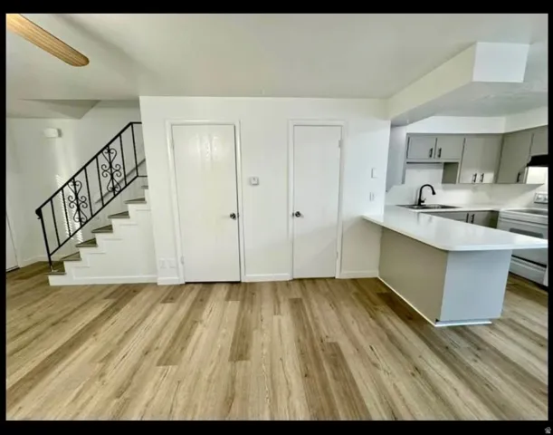 Kitchen with a peninsula, light countertops, white electric range, and light wood-type flooring