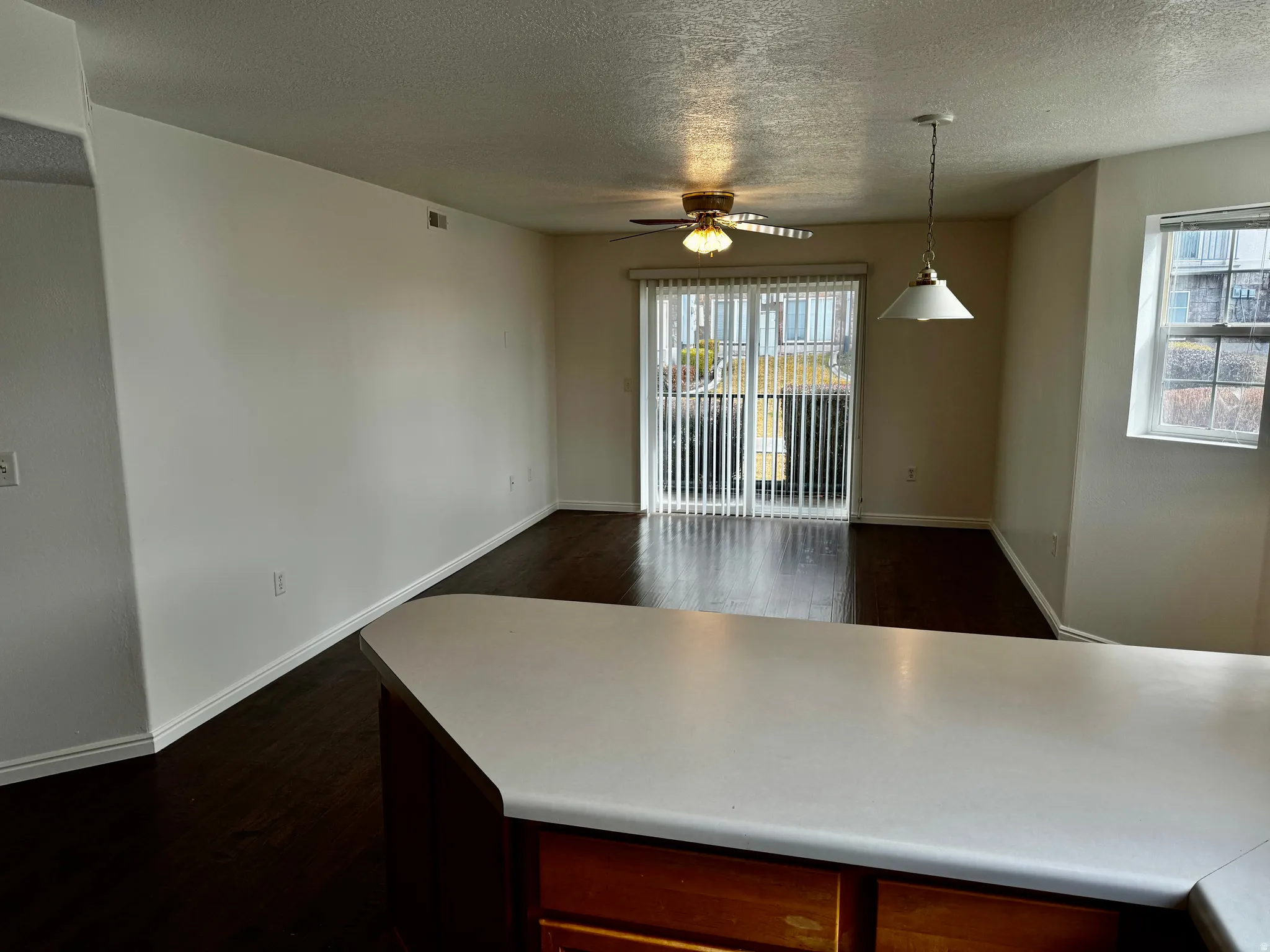Kitchen with dark wood-style flooring, light countertops, a ceiling fan, a textured ceiling, and pendant lighting
