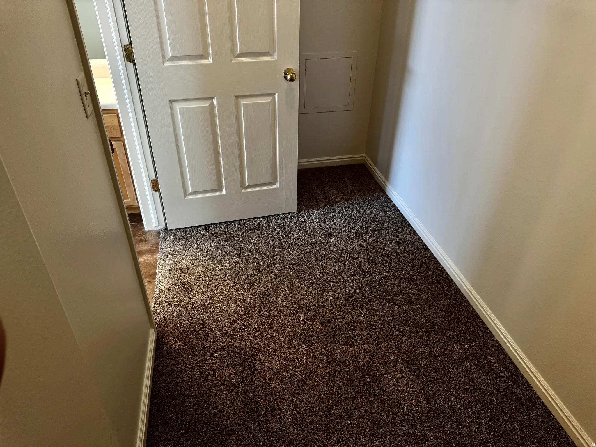 Hall featuring dark colored carpet and baseboards