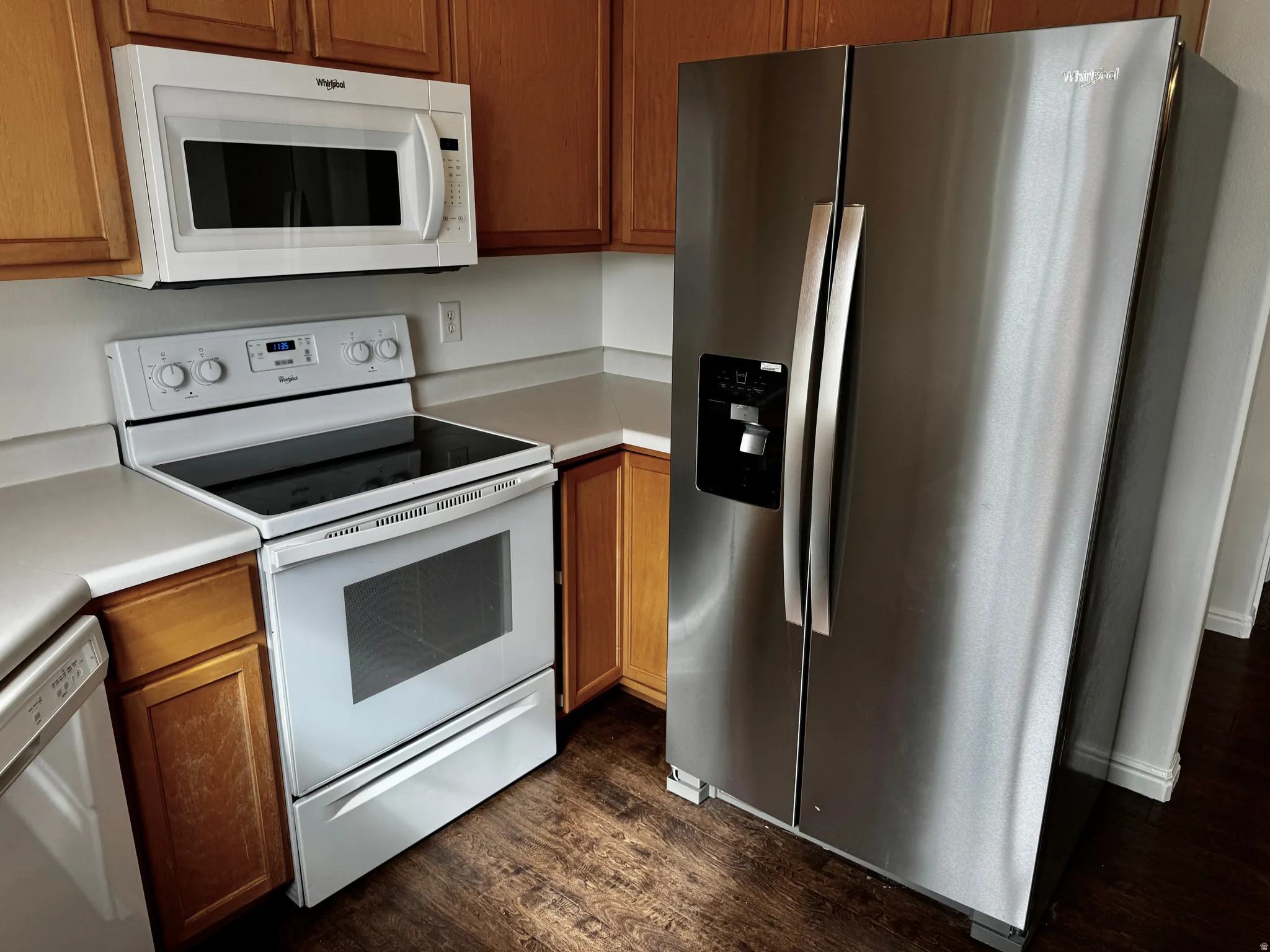 Kitchen featuring white appliances, light countertops, dark wood-style flooring, and wood finish cabinets