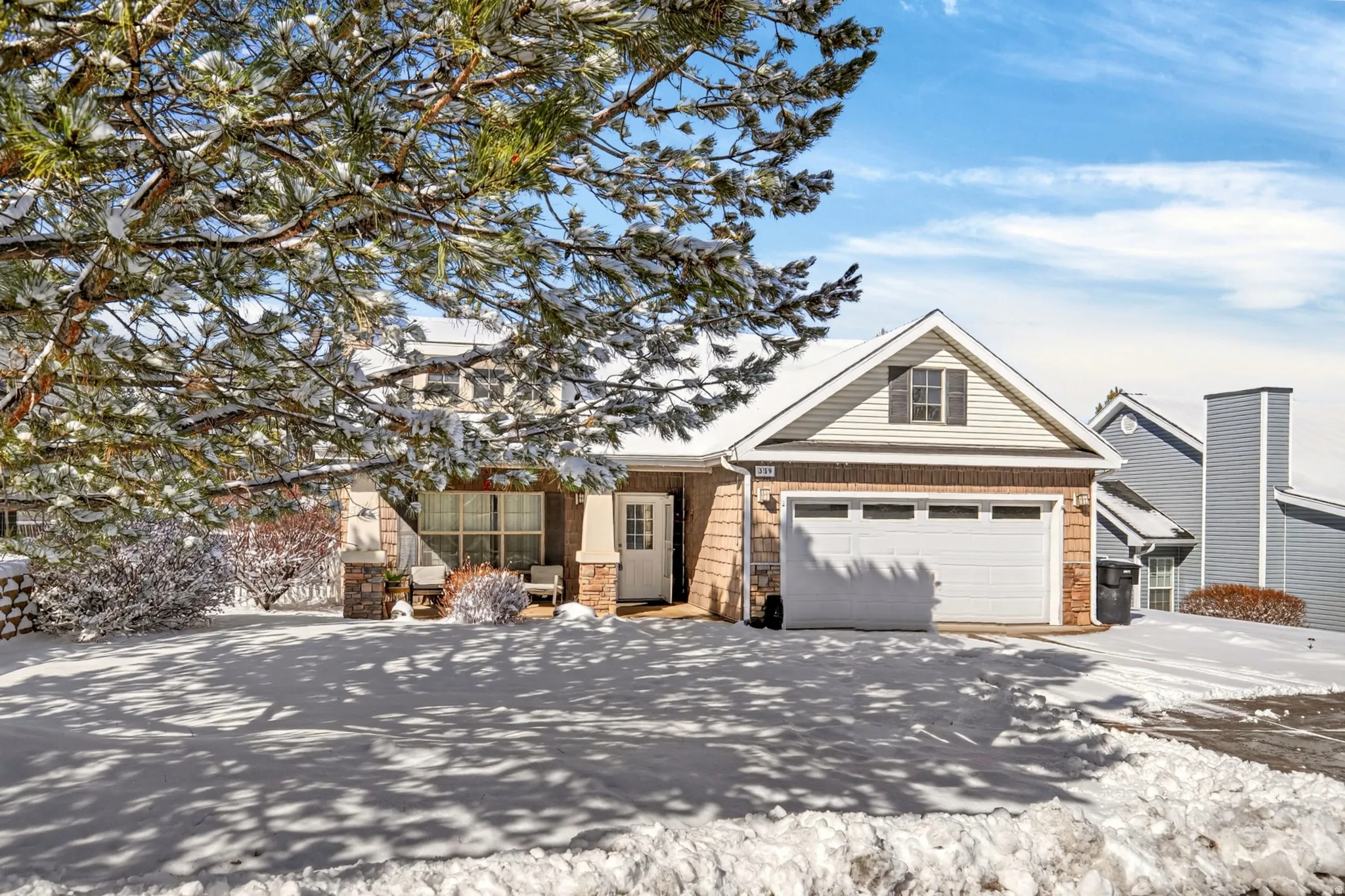 View of front facade featuring stone siding, a garage, and driveway