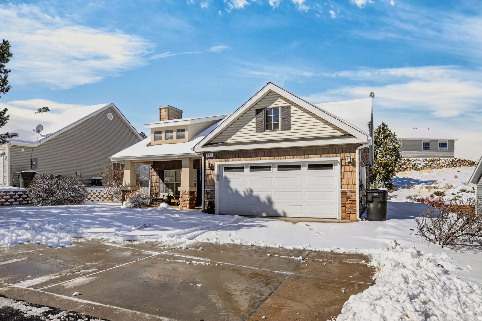 View of front facade featuring stone siding, covered porch, a garage, and a chimney
