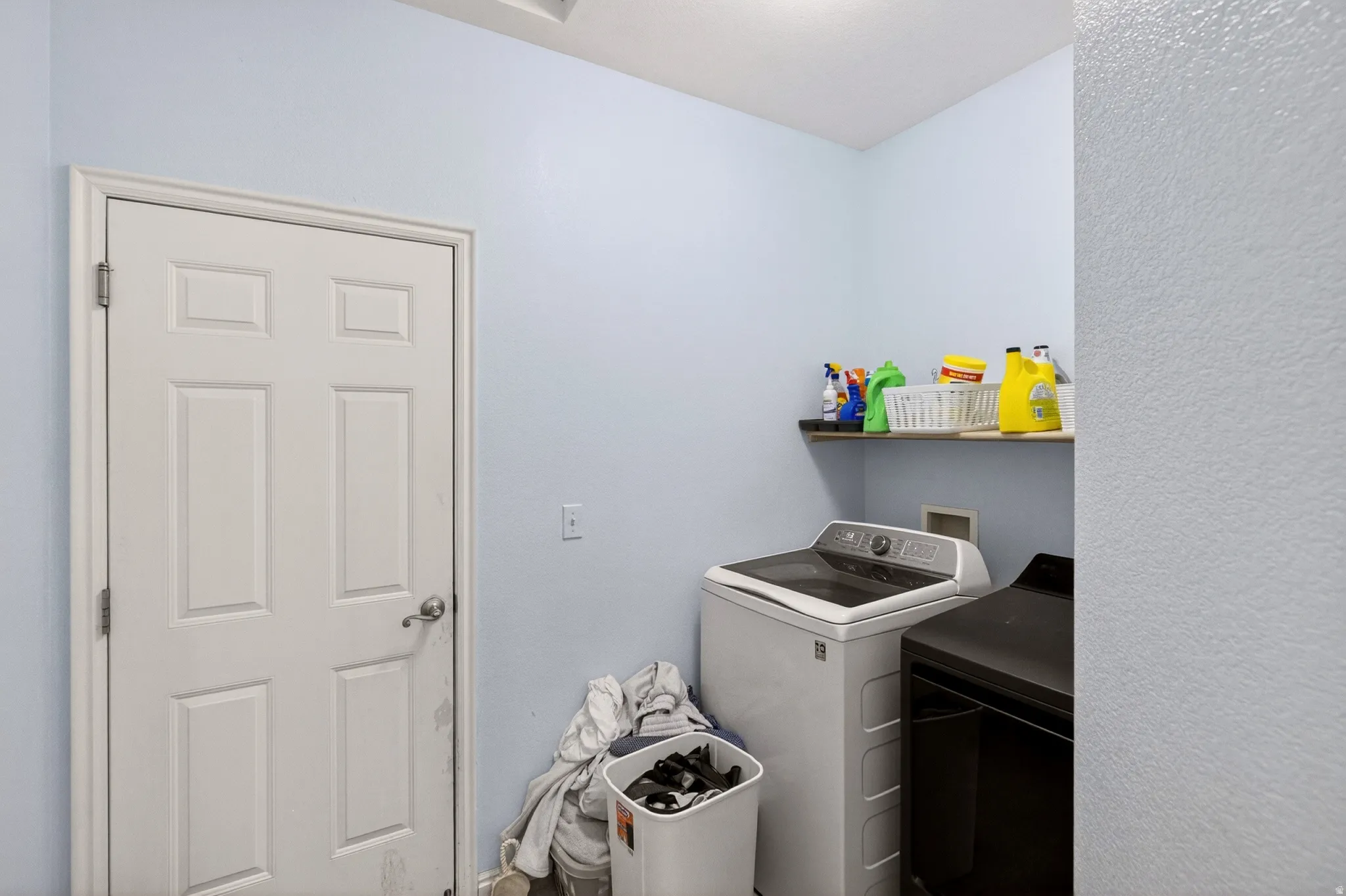 Laundry room featuring a textured wall and washer and clothes dryer