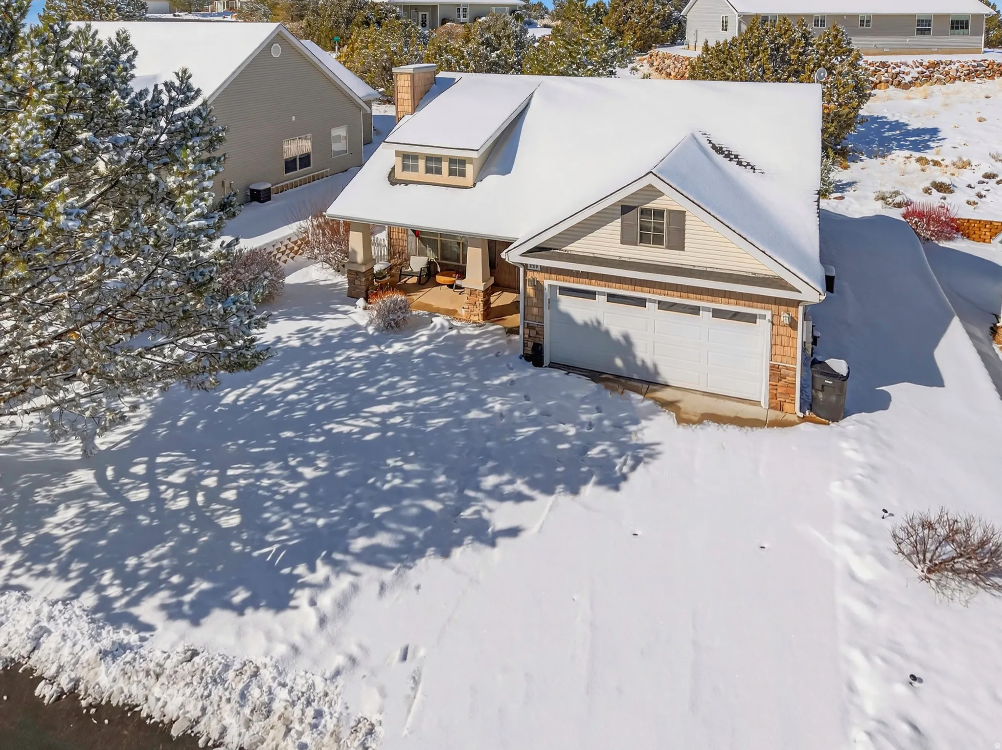 View of front of home featuring stone siding, a chimney, a garage, and a residential view