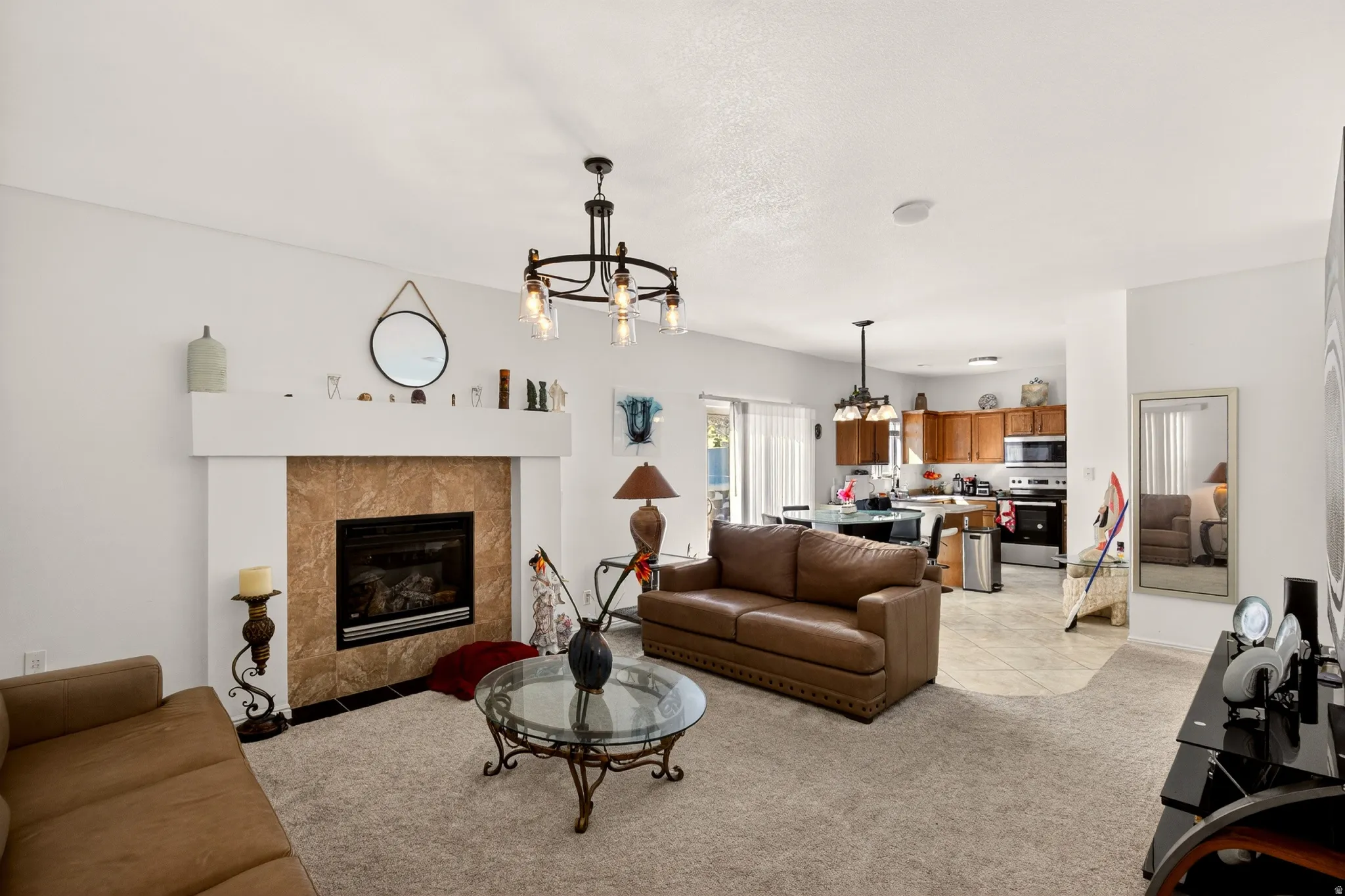 Living room with light carpet, a fireplace, suspended lighting, and light tile patterned flooring