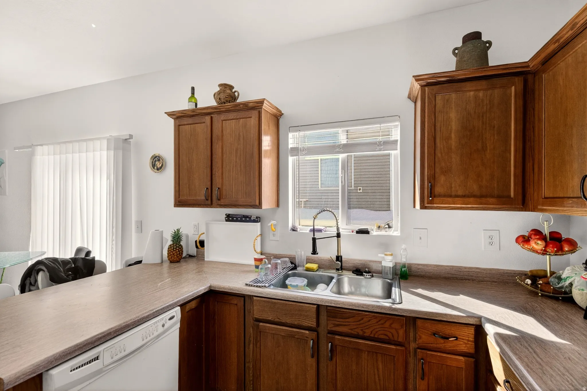 Kitchen with white dishwasher, wood finish cabinets, and a peninsula