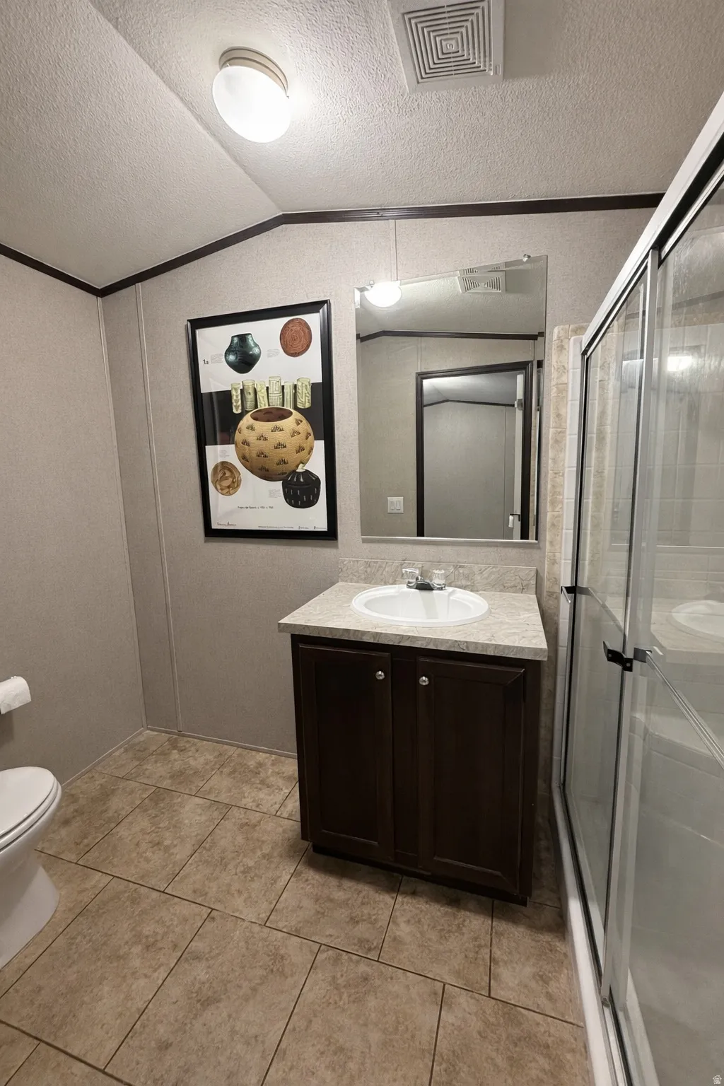Bathroom featuring vanity, a shower stall, crown molding, and light tile patterned floors
