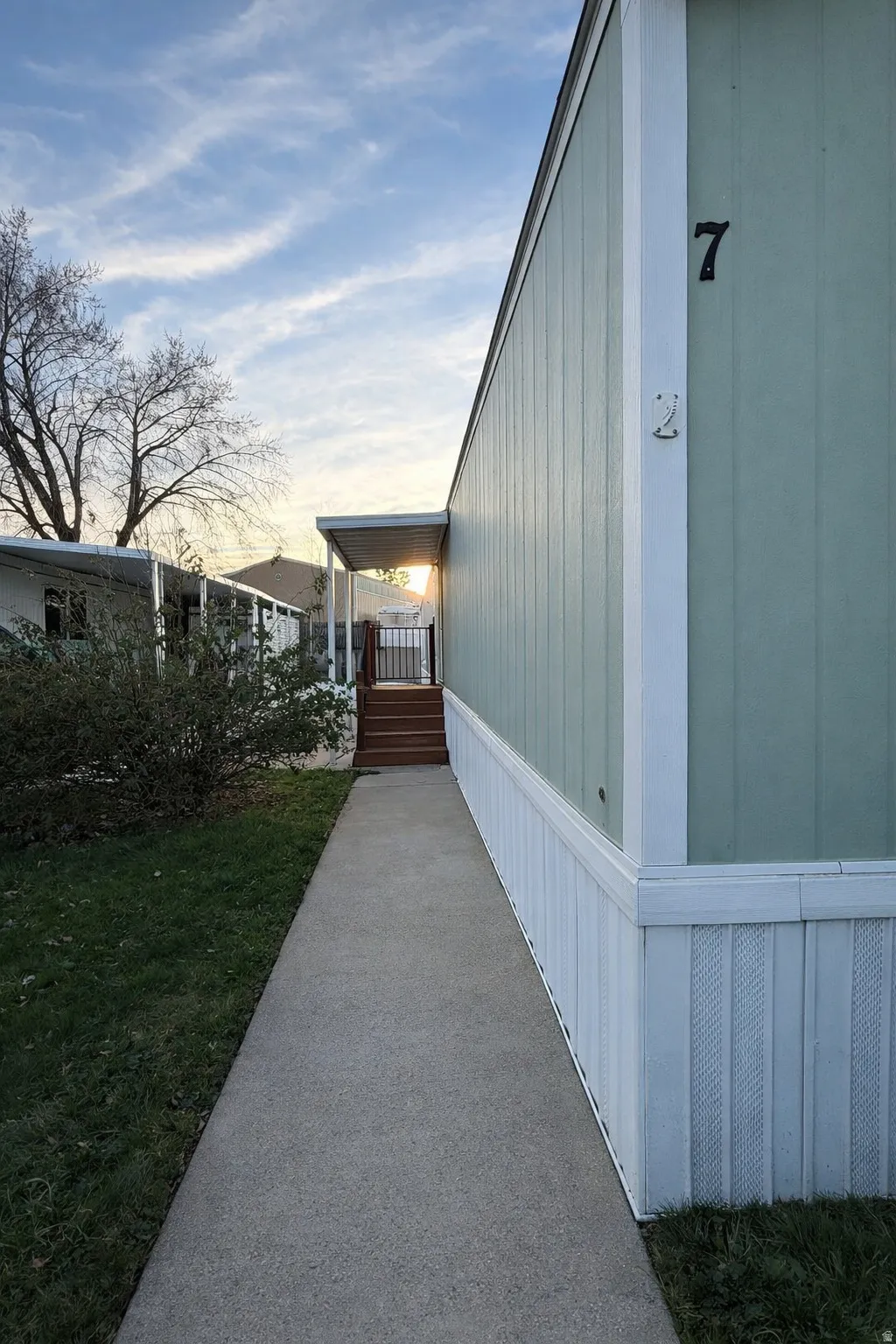 View of side of home with an entry, porch and a lawn