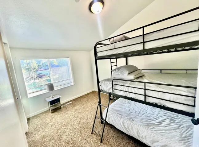Bedroom with light carpet and vaulted ceiling
