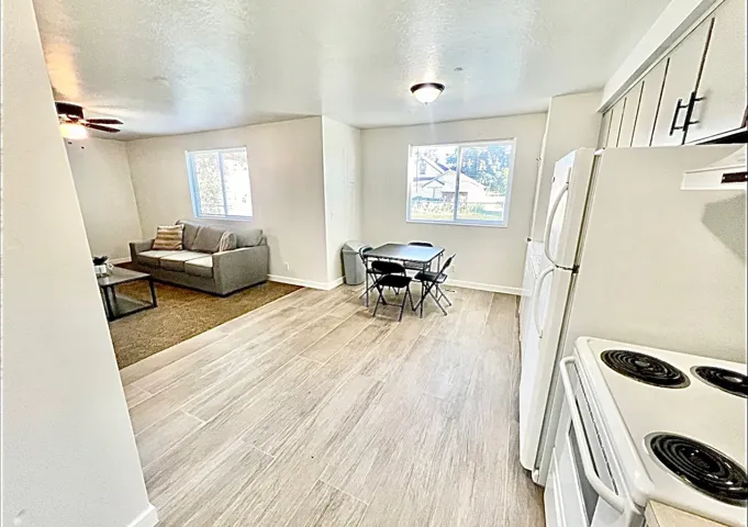 Kitchen with white appliances, light wood finished floors, a textured ceiling, ceiling fan, and light countertops