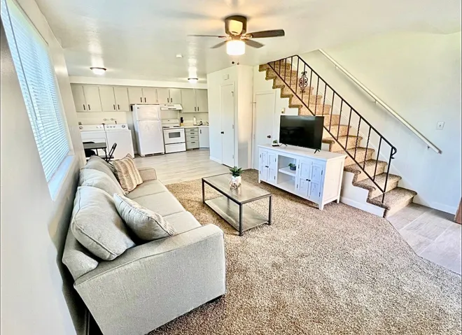 Living area featuring light wood-style flooring, washing machine and dryer, and ceiling fan