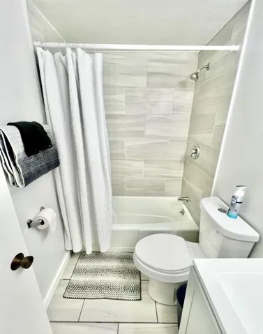 Bathroom featuring vanity, shower / bath combo with shower curtain, and light tile patterned floors