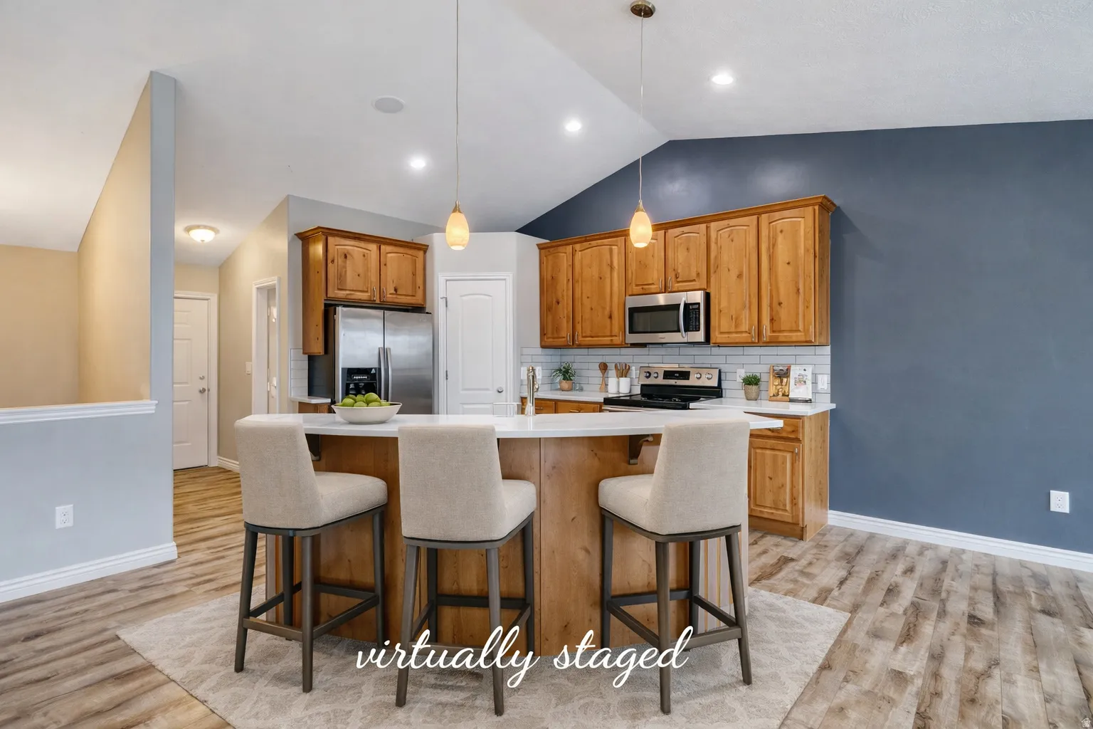 Kitchen with a breakfast bar, a kitchen island with sink, wood finish cabinets, hanging light fixtures, and stainless steel appliances