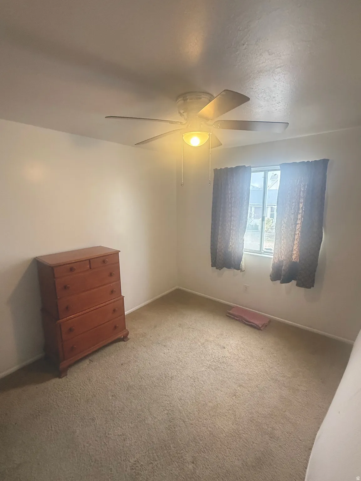 Unfurnished bedroom featuring ceiling fan and light carpet