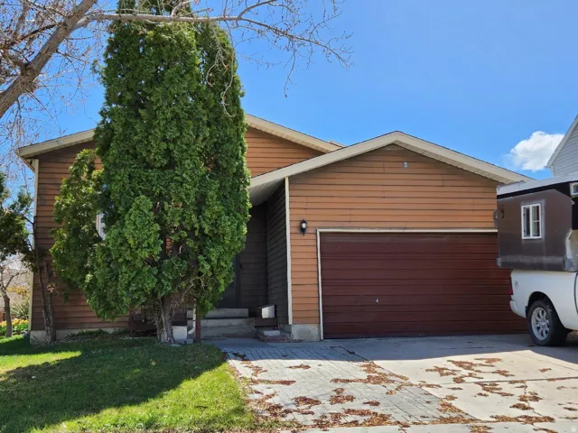 View of front of property with a garage, driveway, and a front lawn