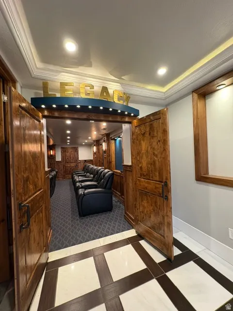 Cinema room featuring inlaid floor details, crown molding, wooden walls, a tray ceiling, and recessed lighting