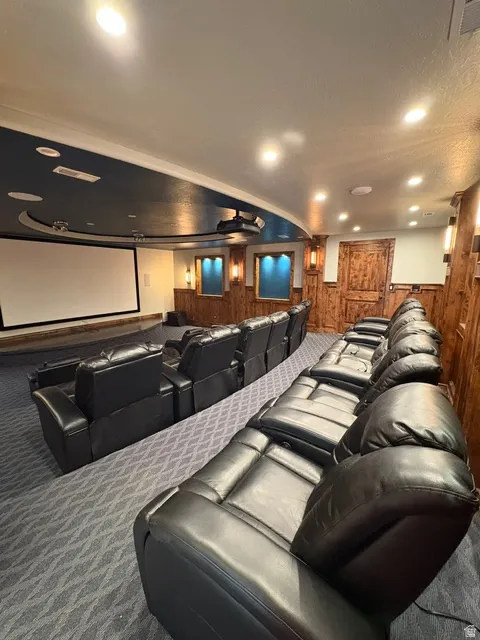 Home theater room featuring wooden walls, carpet flooring, recessed lighting, wainscoting, and ceiling fan