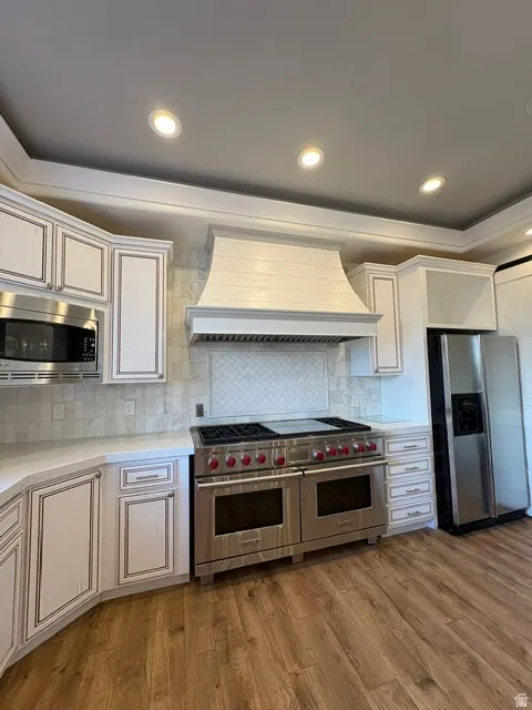 Kitchen featuring stainless steel appliances, dark wood finished floors, backsplash, recessed lighting, and light stone counters