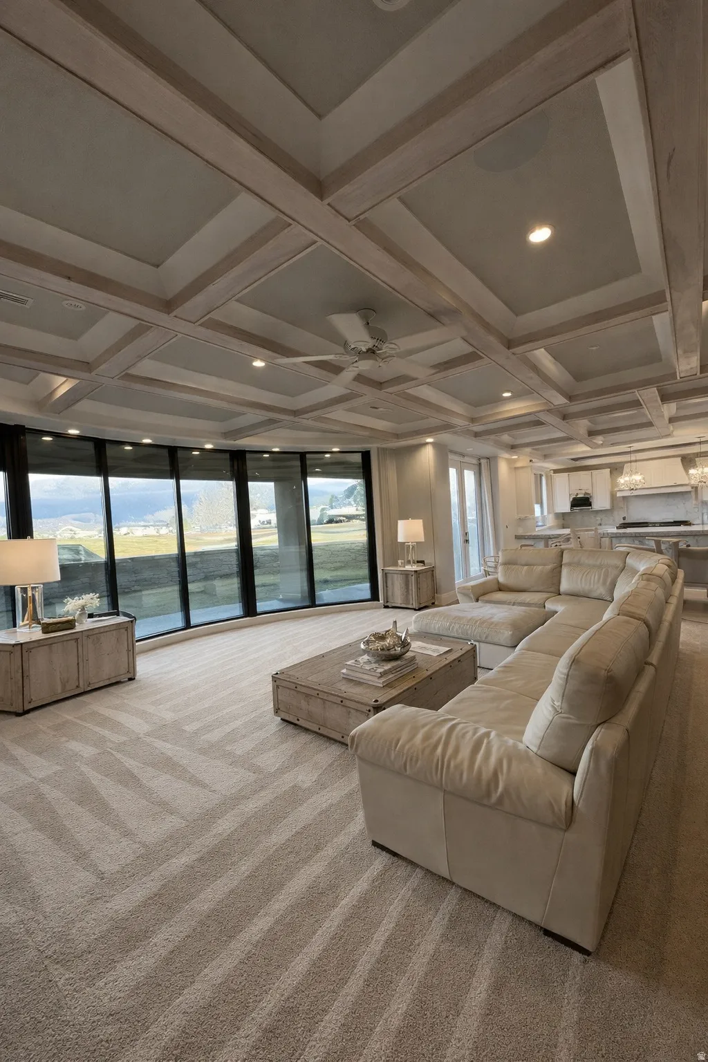 Carpeted living room with coffered ceiling, ceiling fan, recessed lighting, and a water view