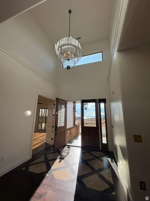 Entryway with inlaid floor details, a chandelier, a high ceiling, and plenty of natural light