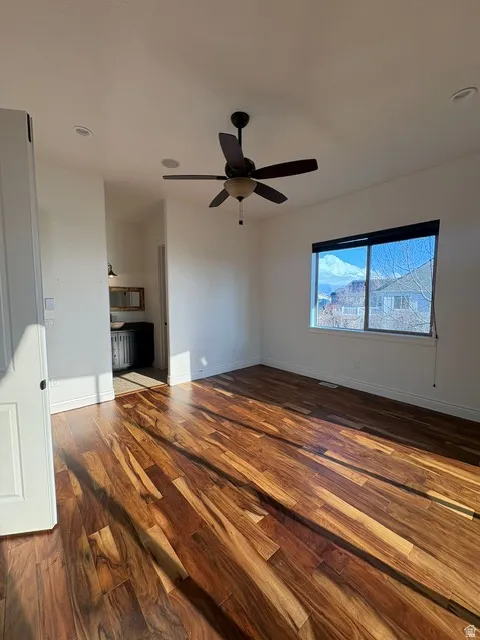 Unfurnished living room featuring dark wood-type flooring, ceiling fan, and recessed lighting