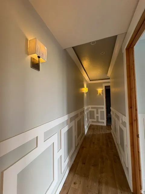 Hallway featuring a wainscoted wall, a decorative wall, and dark wood finished floors