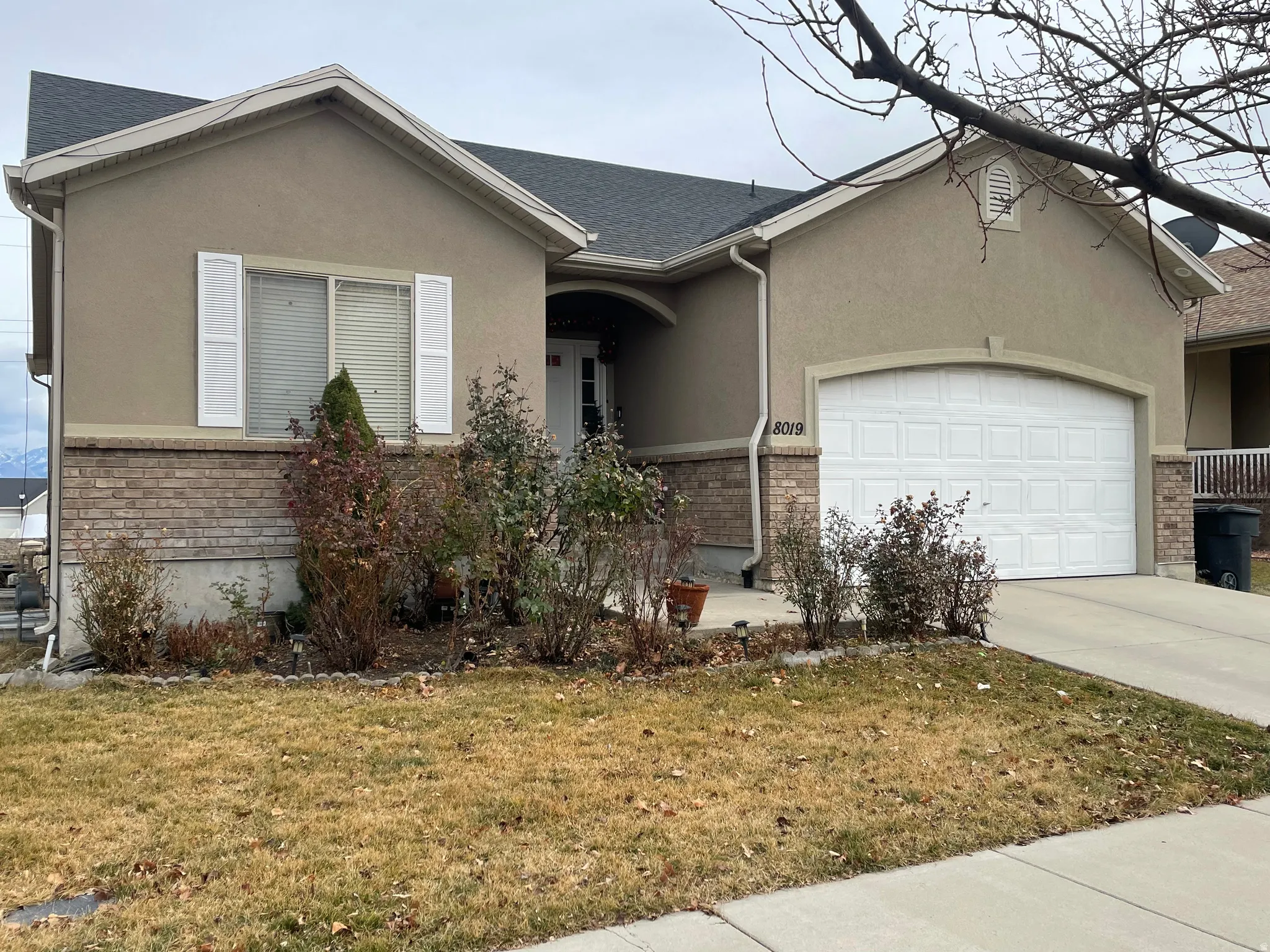Ranch-style house featuring an attached garage, a front lawn, driveway, and stucco siding