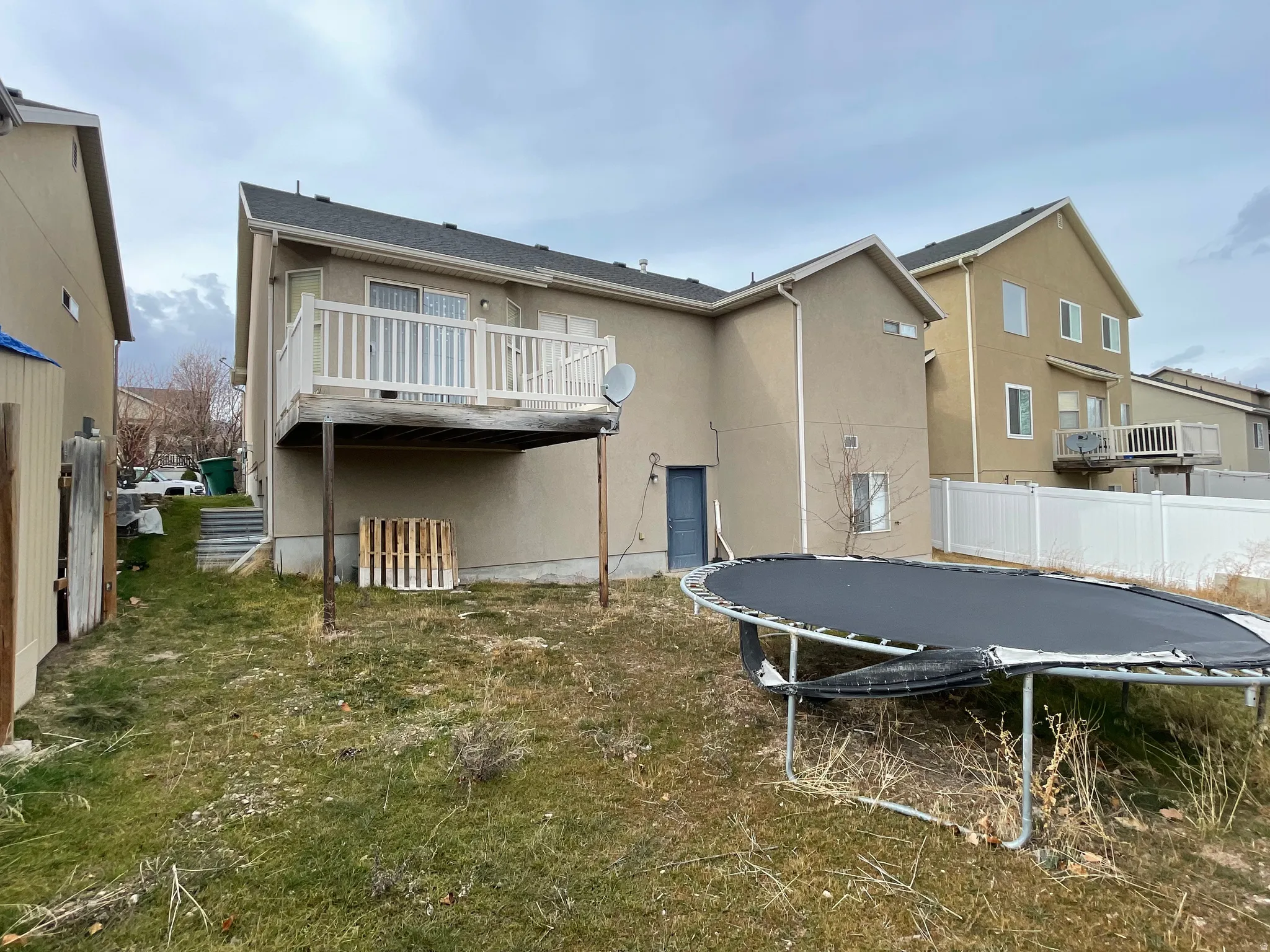 Back of house with a trampoline, stucco siding, and a wooden deck