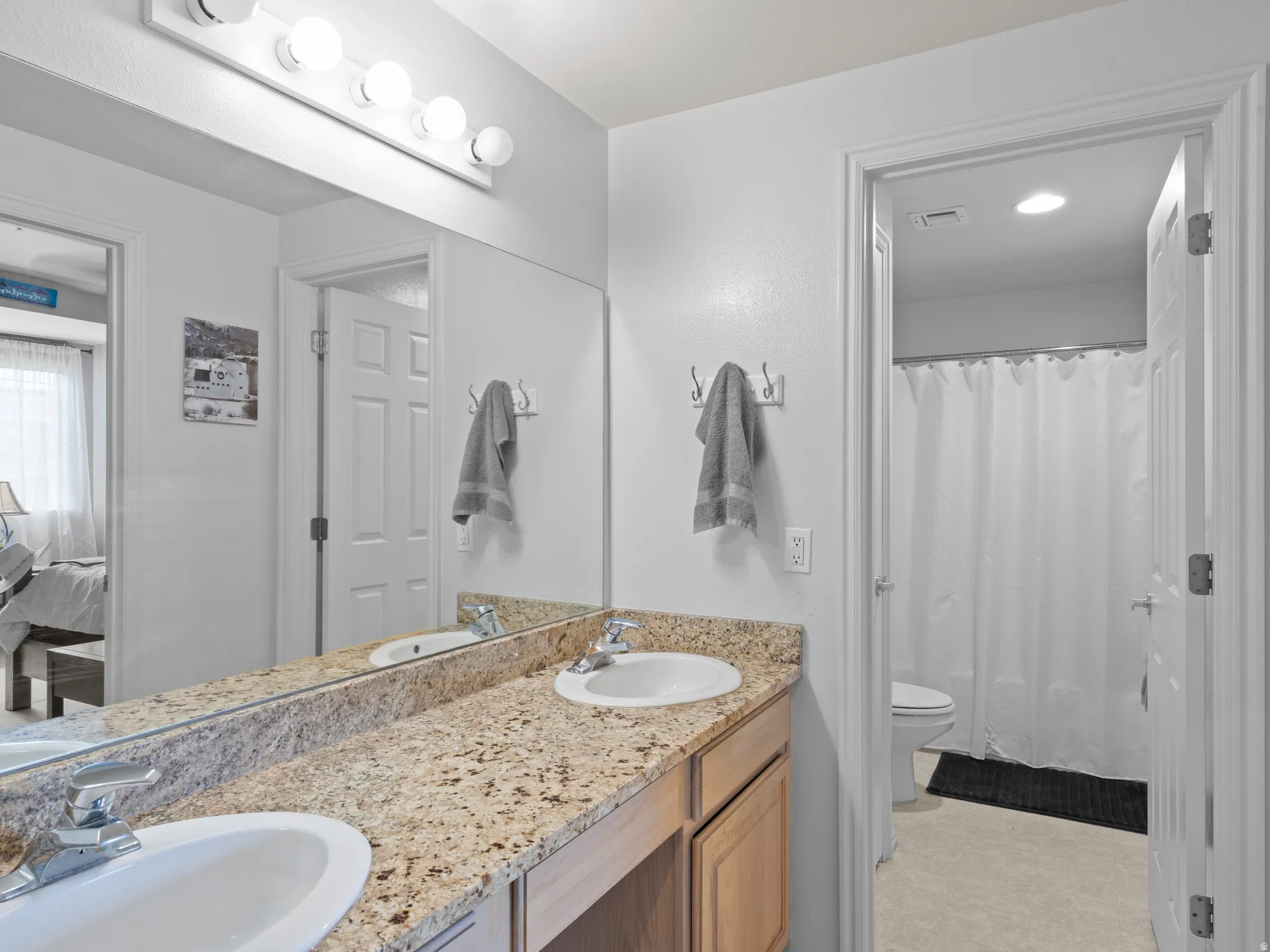 Ensuite bathroom featuring double vanity and light flooring