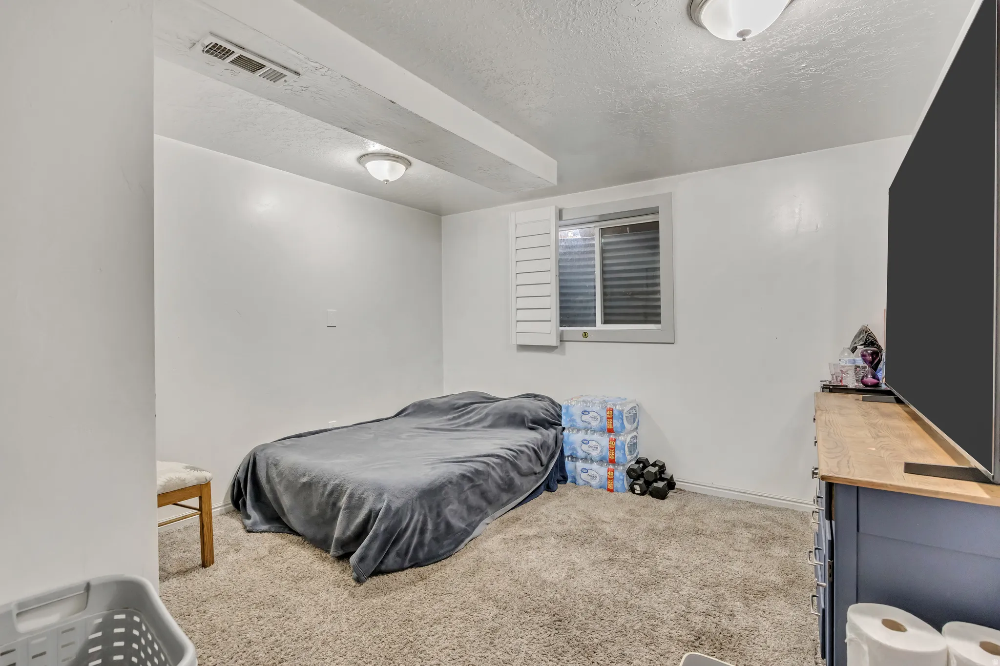 Bedroom with light colored carpet and a textured ceiling