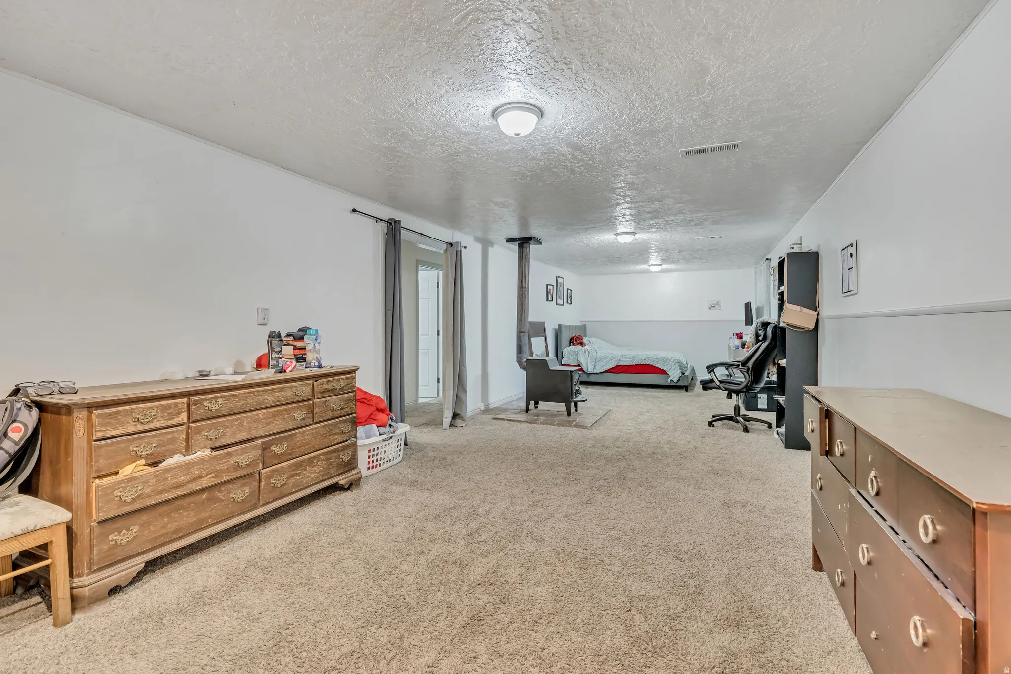 Bedroom with a textured ceiling and light colored carpet