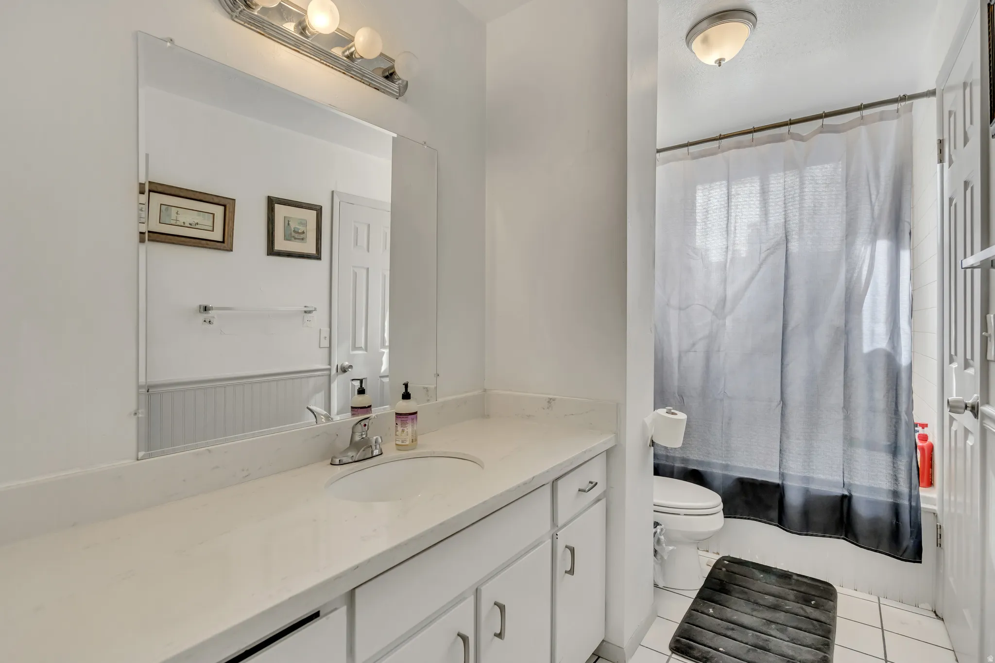 Bathroom featuring vanity, shower / bath combo with shower curtain, and light tile patterned floors