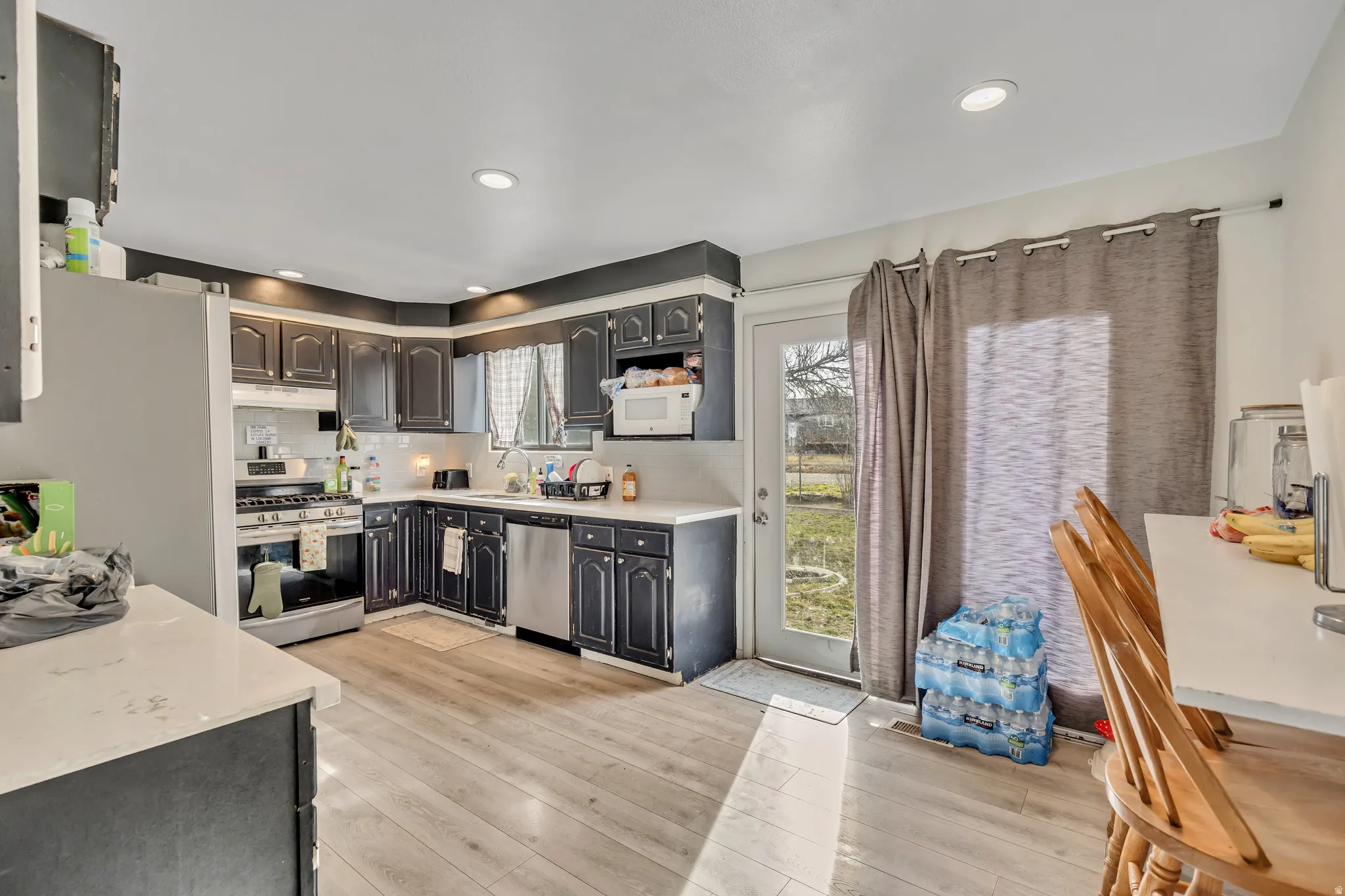 Kitchen featuring stainless steel appliances, light wood finished floors, decorative backsplash, and recessed lighting