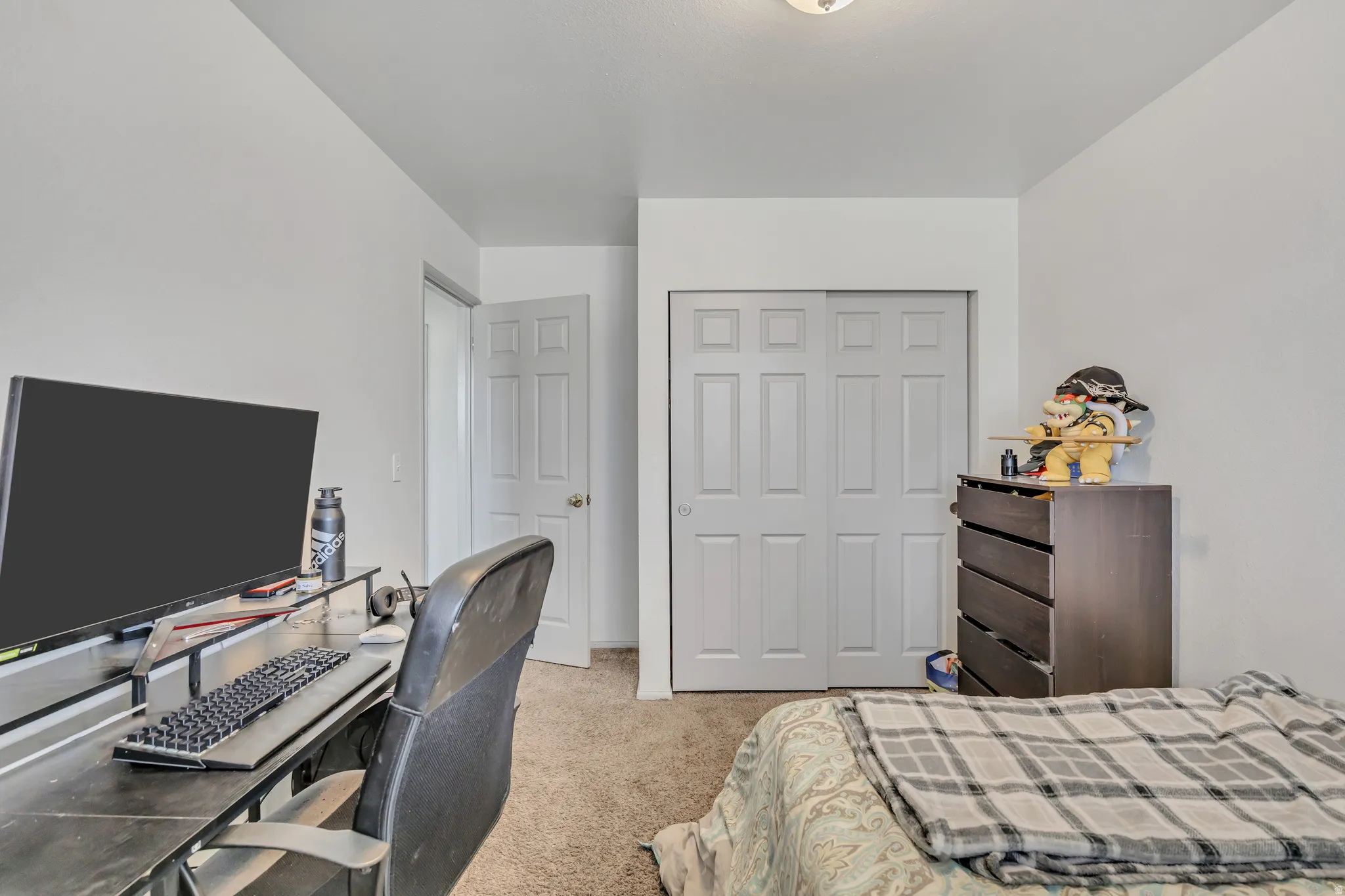 Bedroom featuring an office area, light colored carpet, and a closet