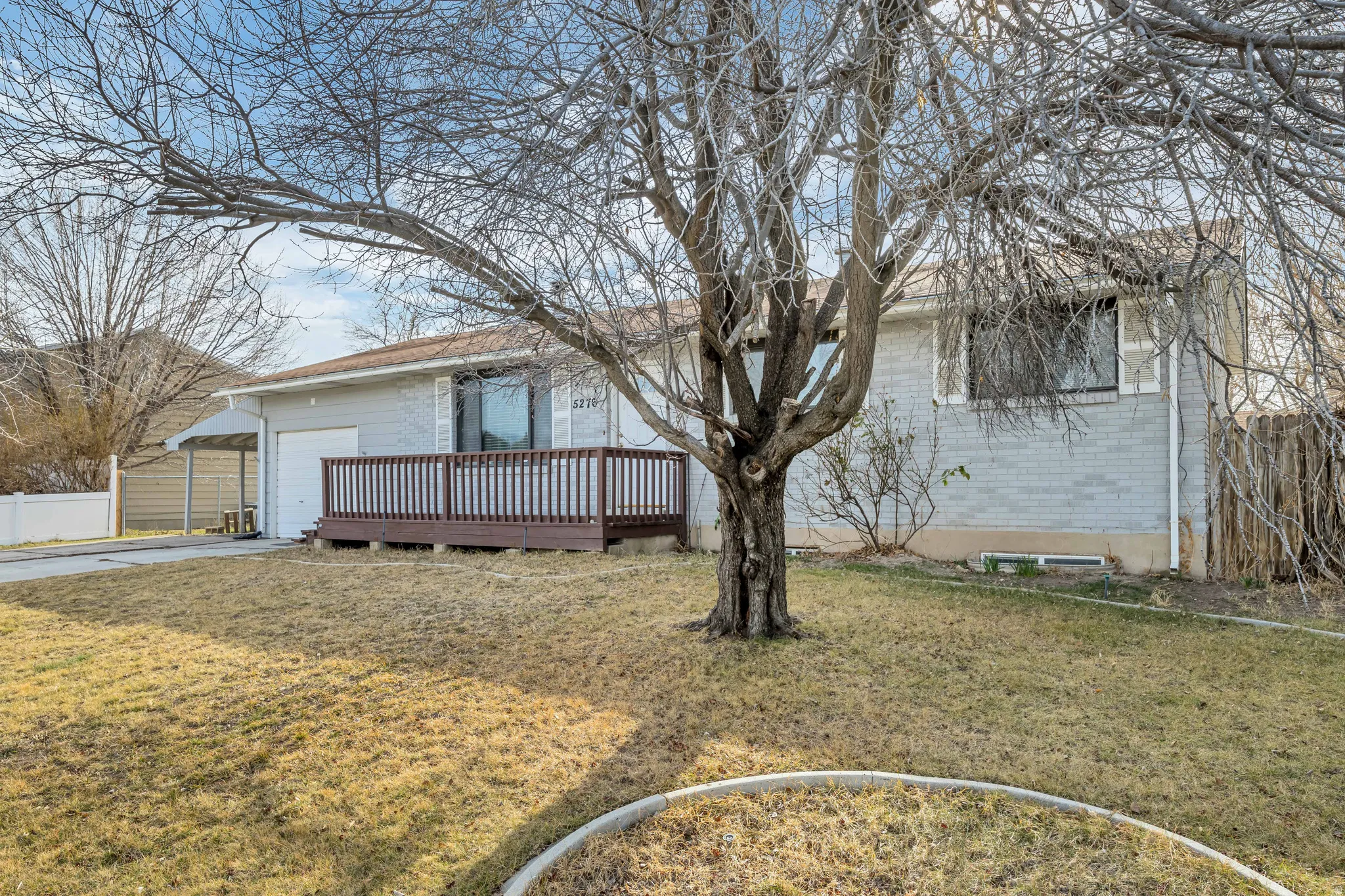 View of side of property with brick siding, a deck, an attached garage, and concrete driveway