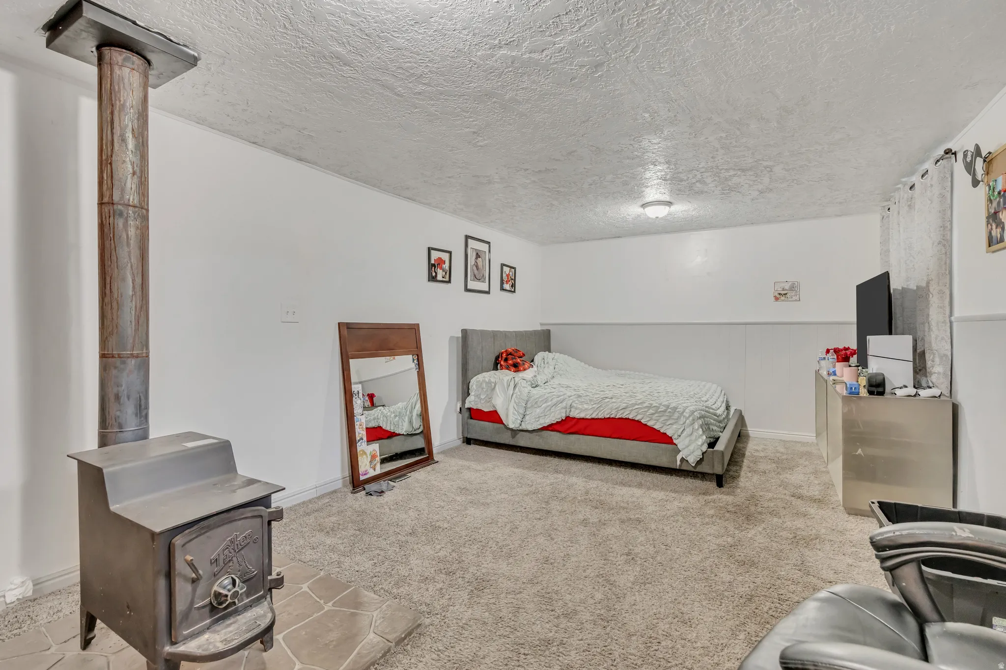 Bedroom featuring a wood stove, a textured ceiling, and light carpet