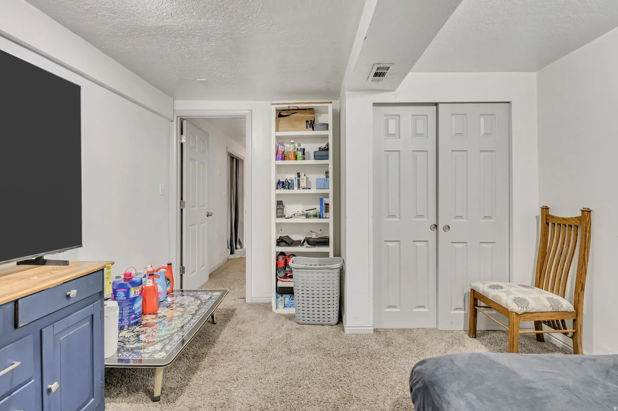 Bedroom featuring a textured ceiling, a closet, and light colored carpet