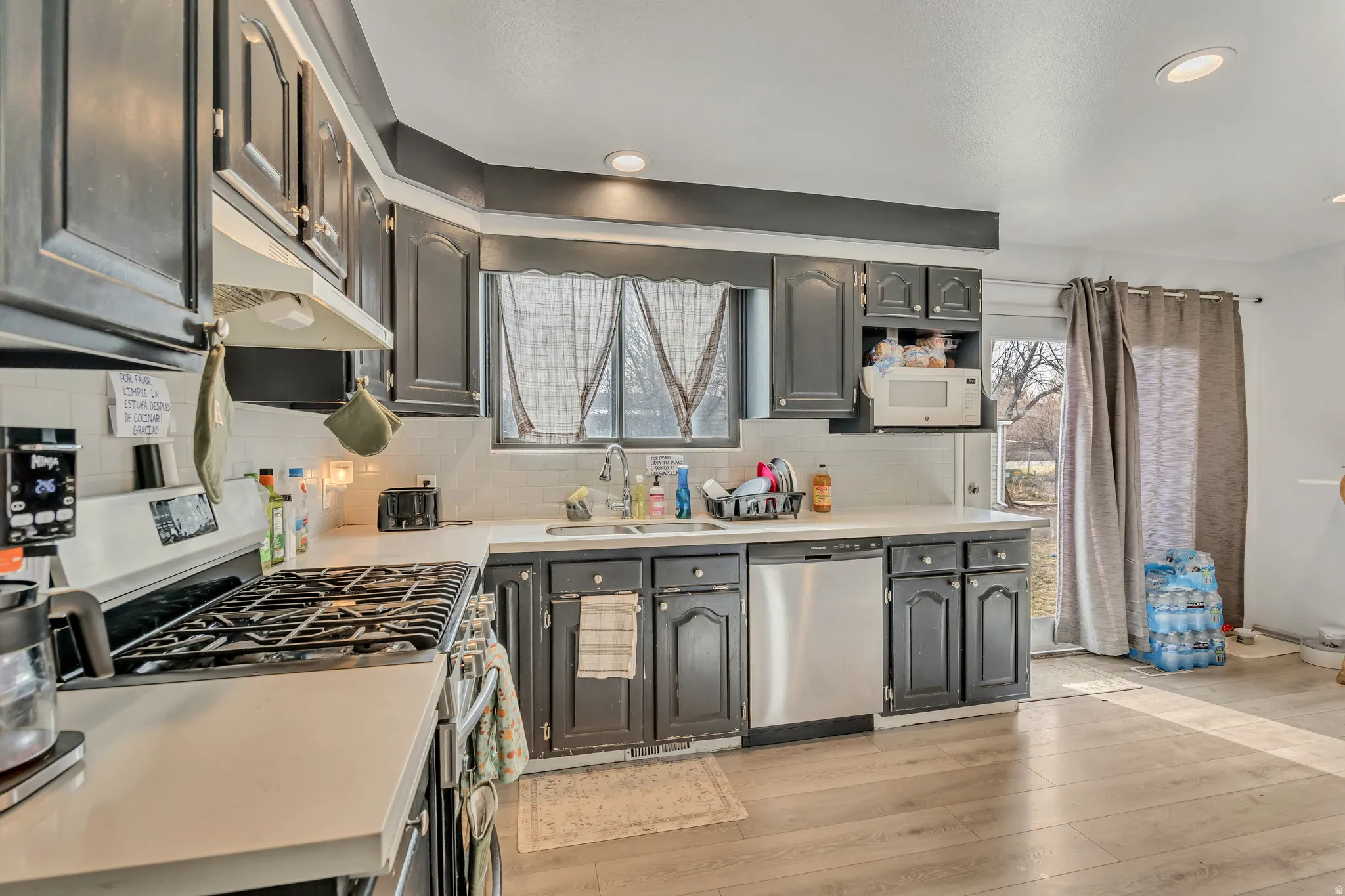 Kitchen featuring stainless steel appliances, light countertops, light wood finished floors, recessed lighting, and backsplash