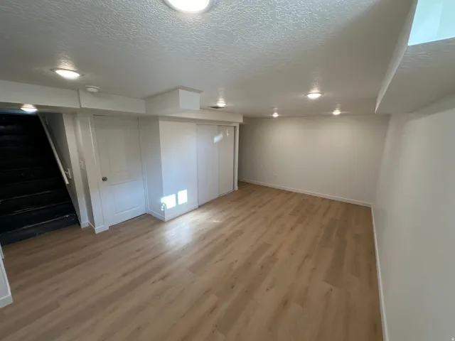 Finished basement with a textured ceiling and light wood-type flooring