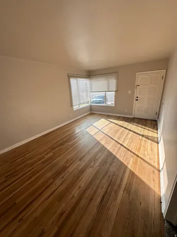Unfurnished living room with hardwood / wood-style floors and baseboards