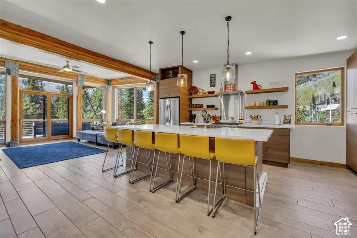 Open great room featuring a modern, custom kitchen and floor to ceiling windows
