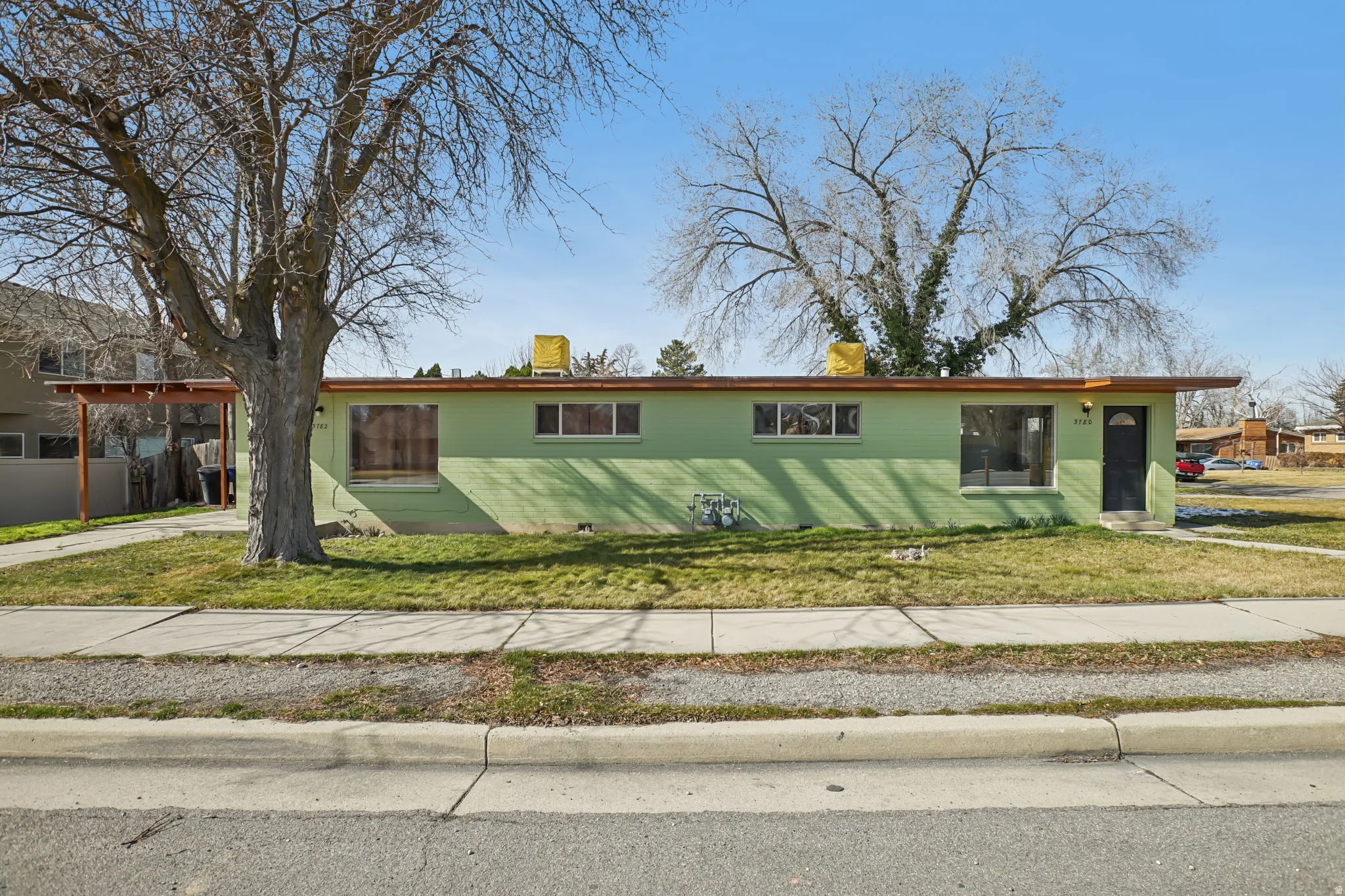 Ranch-style side by side duplex featuring a front lawn and a carport