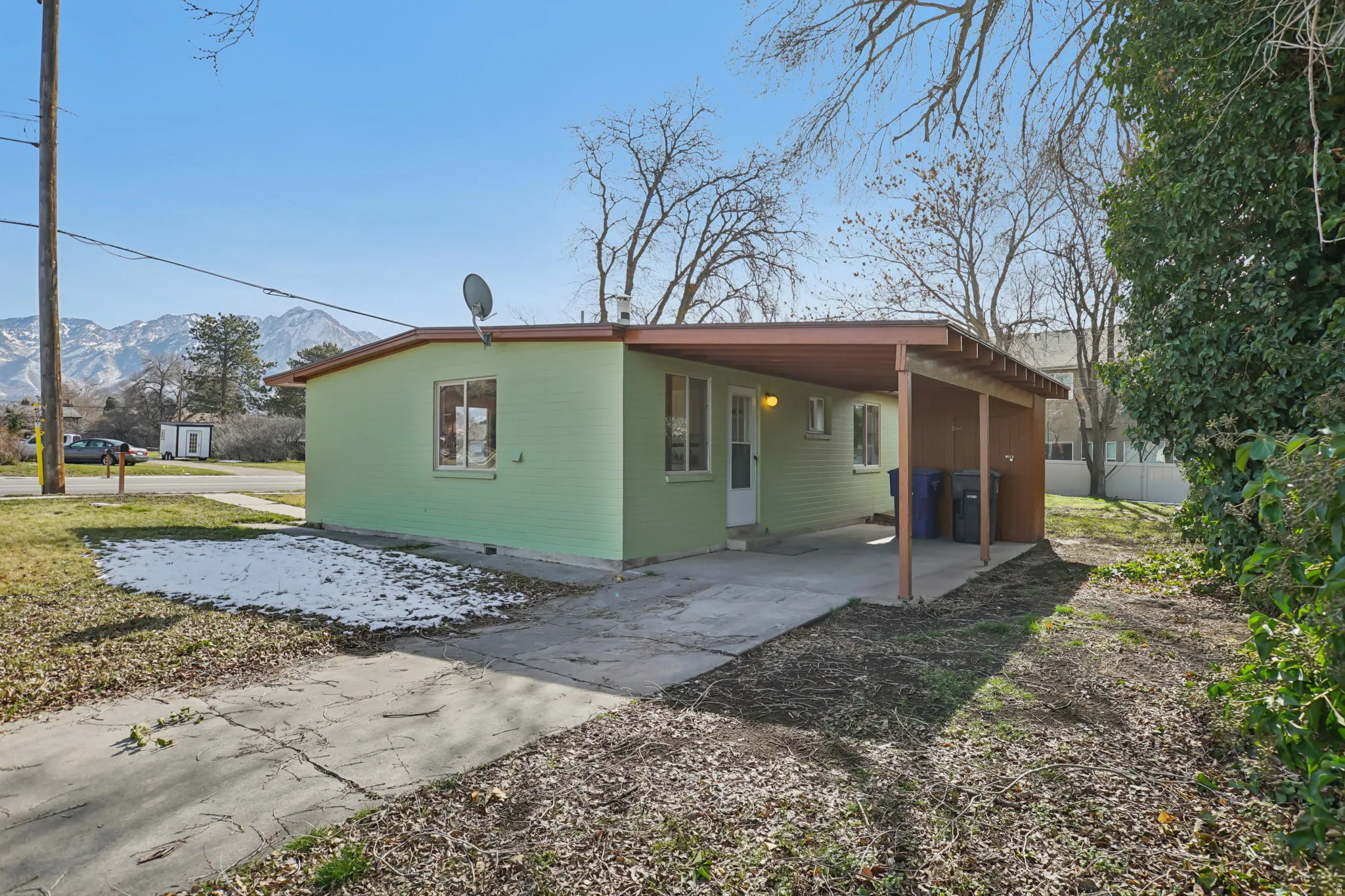 View of home's exterior with a carport, driveway, a mountain view, and a patio