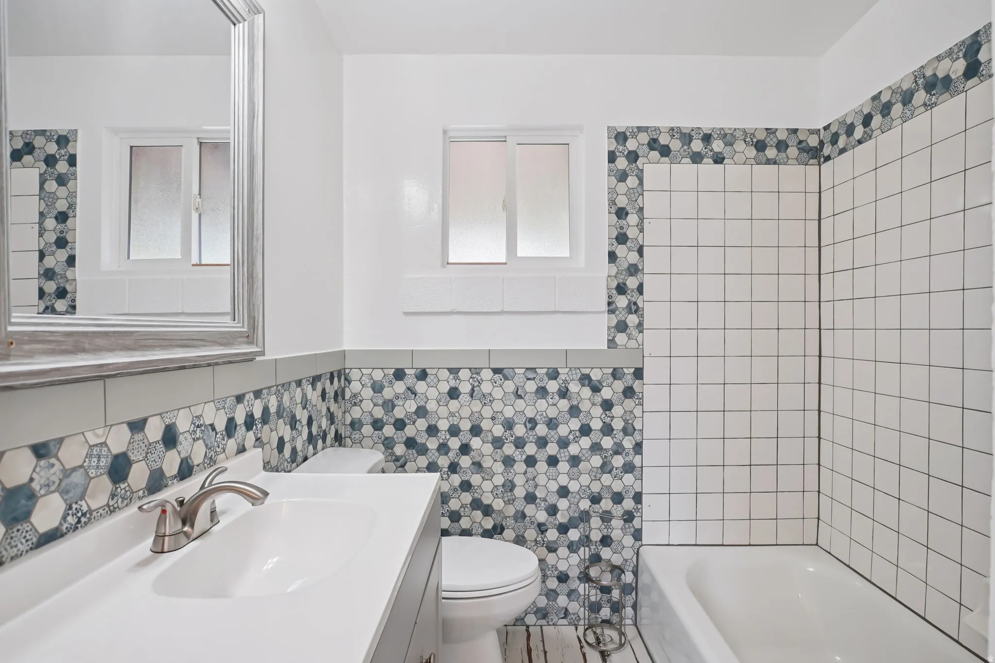 Updated bathroom with tile walls, vanity, a wainscoted wall, and shower / washtub combination