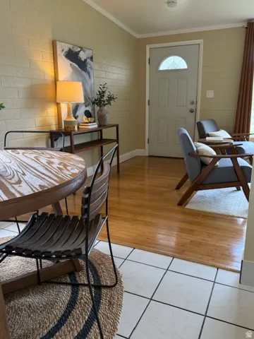 Dining area featuring crown molding, light wood-style floors, and concrete block wall